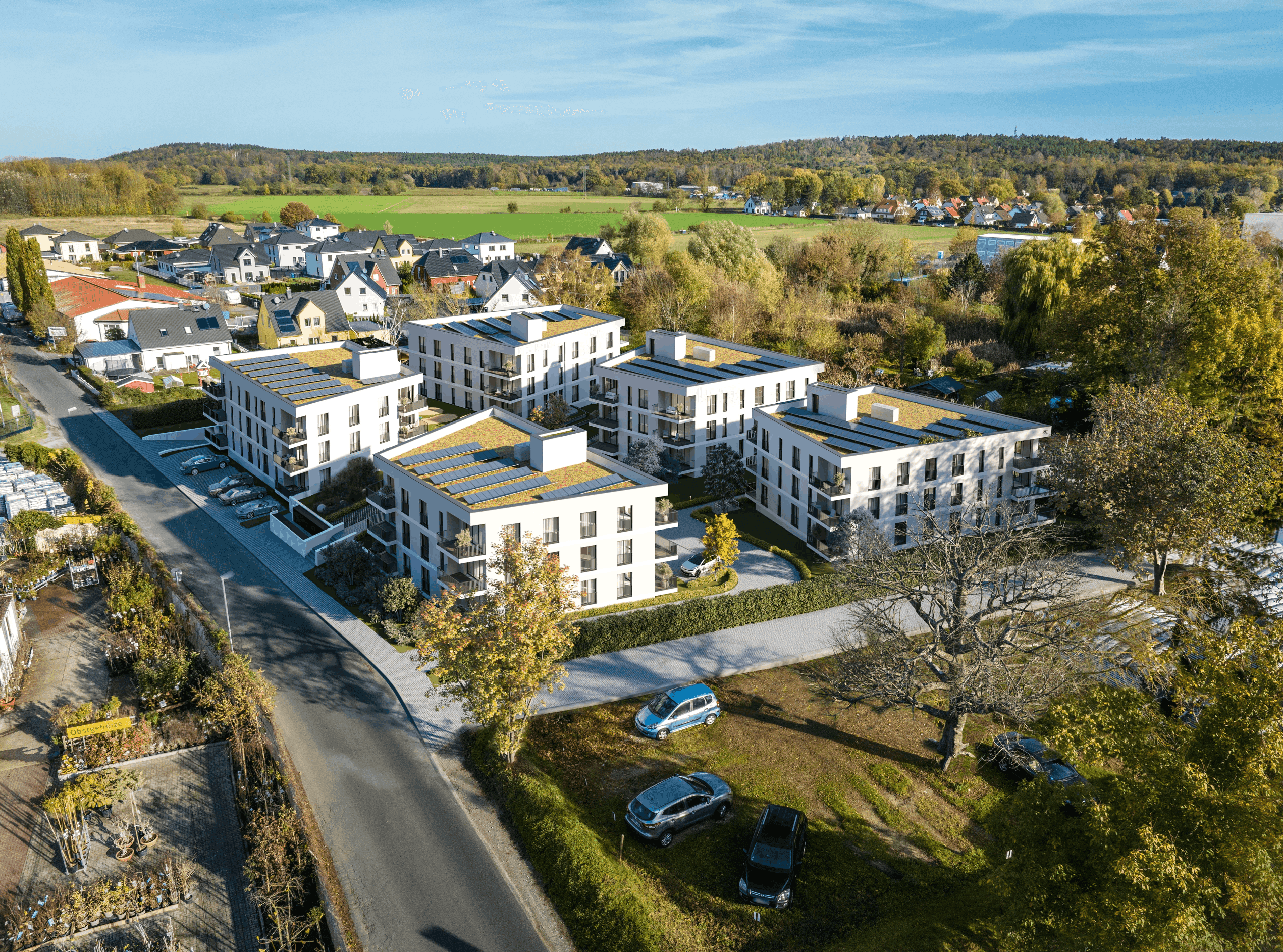 Fotorealistische 3D-Architekturvisualisierung eines modernen Neubauquartiers aus der Vogelperspektive. Die detaillierte Luftaufnahme zeigt ein geplantes Wohnprojekt mit mehreren weißen Mehrfamilienhäusern, die mit nachhaltigen Gründächern und Photovoltaikanlagen ausgestattet sind. Moderne Balkone, großzügige Fensterfronten und ansprechende Außenanlagen mit Parkplätzen runden das Architekturkonzept ab. Die Gebäude fügen sich harmonisch in die umliegende grüne Vorstadtlandschaft ein – ein ideales Bild für die professionelle Immobilienvermarktung und Projektentwicklung.